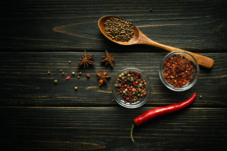 Various spices and peppers on a black table. Seasonings in glass cups and a spoon. Dark space for recipe or menu.の写真素材