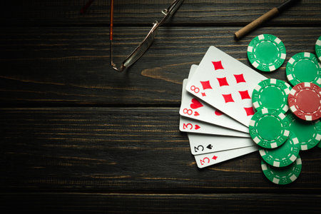 Playing poker with a winning combination of full house or full boat. Cards with chips on a black vintage table in a poker club.の写真素材