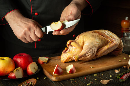 The cook cuts apples to add to raw duck before frying. Cooking a national dish or Peking duck in the restaurant kitchen by the hands of the chef.の写真素材