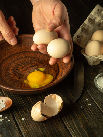 Delicious egg by the hands of the chef in the kitchen of the restaurant. The cook holds raw eggs before cooking. Egg diet food.の写真素材