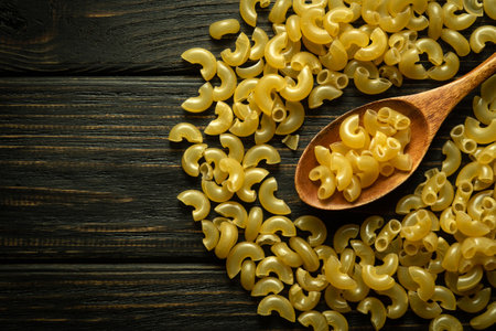 Scattered pasta on a vintage table and in a spoon. The concept of cooking pasta on the kitchen table. Dark space for menu or recipeの写真素材