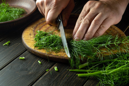 The chef hands cutting fresh foeniculum on a kitchen cutting board before preparing national or...