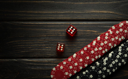 Poker dice or dice game on a black wooden table and chips from a lucky win. Free dark space for ads....