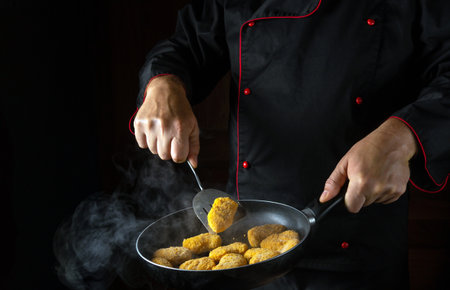 Cooking crispy chicken nuggets. The chef flips the nagits in a smoky hot pan. The idea of a large kitchen for a hotel with an advertising space.の写真素材