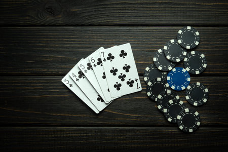 Popular poker game with straight flush winning combination. Cards with chips on a black vintage...