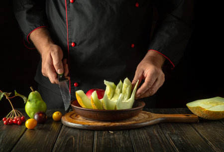 The chef puts fruit on a plate for serving on the festive table. The concept of a fruit diet in a restaurant kitchen. Asian national cuisine.の写真素材