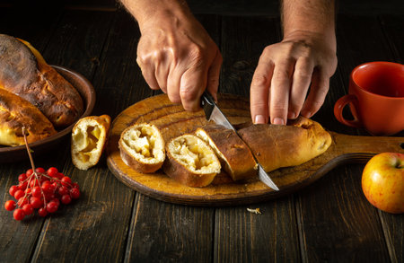 A baker slices a fresh pie with apples for serving the holiday table. Delicious apple pie with aromatic tea.の写真素材