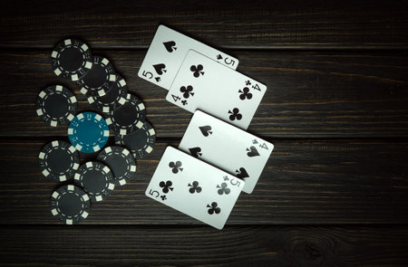 Gambling and interesting game of poker with a combination of two pairs. Chips and cards on a dark...