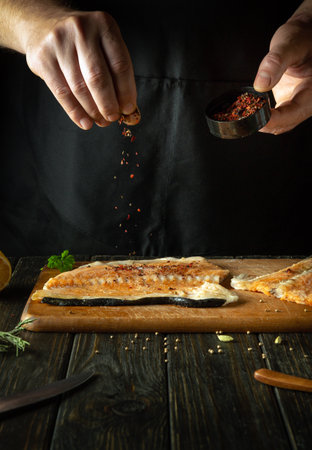 Adding dry spices to fish steaks for aroma and taste. American cuisine. The process of preparing...