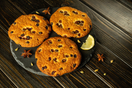 Oatmeal cookies with raisins, spices and lemon on a black serving board, prepared for breakfast or lunch.の写真素材