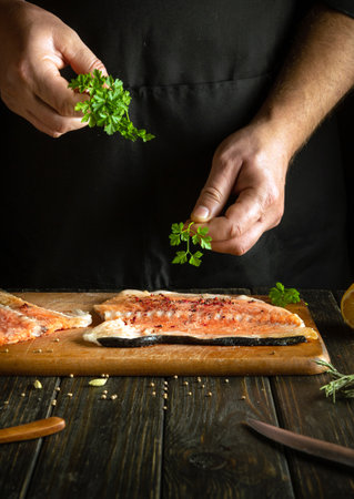 Fragrant parsley for fish in the hands of a cook. The process of preparing salmon fish by the hands of a chef in a hotel kitchen.の写真素材