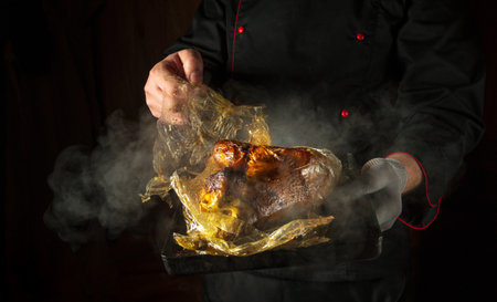 The chef removes the plastic pouch from the duck after baking or sous vide cooking. Concept of cooking poultry on the grill or in a restaurant kitchen. Black space for advertising.の写真素材