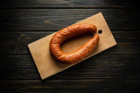 Sausage on a cutting board in a restaurant. Meat food concept with smoked sausage on vintage table in pub or saloon.の写真素材