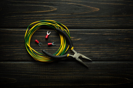 Wire with terminals and pliers on a vintage table for repairing electrical equipment. Concept of...