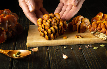 Close-up of a chef hands sorting raw fresh Flammulina velutipes or velvet shank mushrooms on a...
