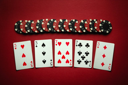 Winning at the poker club. Combination of full house or full boat playing cards and chips on a red...