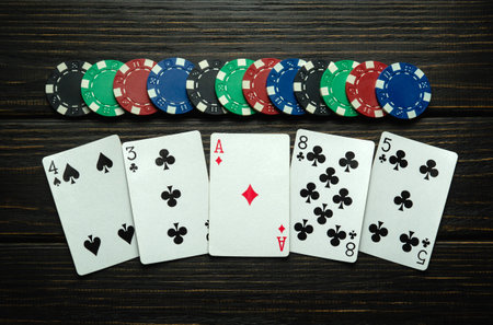 Chips and playing cards with a winning high card combination on a black vintage table. Low key...