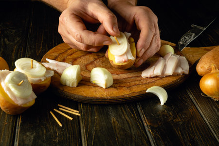 A quick snack dish of lard and potatoes with onions prepared by the cook on a cutting board. Quick meal concept for students.の写真素材