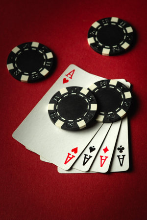 Four aces and black chips on a red table in a casino. Concept of winning with a four of a kind or...