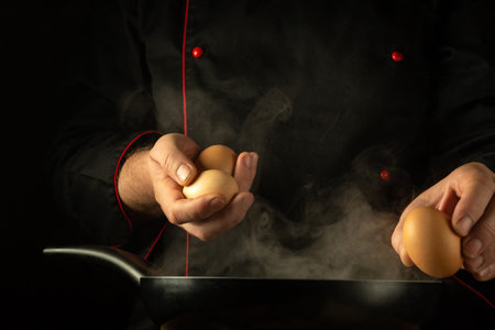 The cook is trying to break an egg to cook scrambled eggs in a frying pan. Low key concept of preparing a delicious lunch in a tavern kitchen. European cuisine.の写真素材