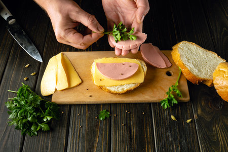 Bread sausage and cheese on a kitchen board for making sandwiches. The cook prepares a quick meal with sandwich and parsley.の写真素材