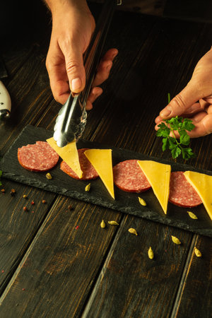 Making breakfast with sausage and cheese. The chef serves a cutting board for appetizers on the kitchen table. Advertising space.の写真素材