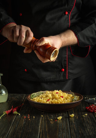 Cooking a delicious pasta dinner. The cook adds pepper to the food with a hand mill.の写真素材