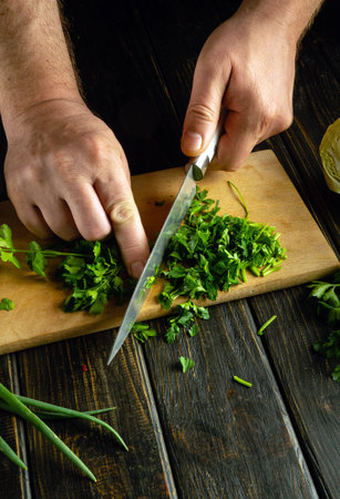A cook chops fresh parsley with a knife on a cutting board to prepare a flavorful breakfast dish.の写真素材