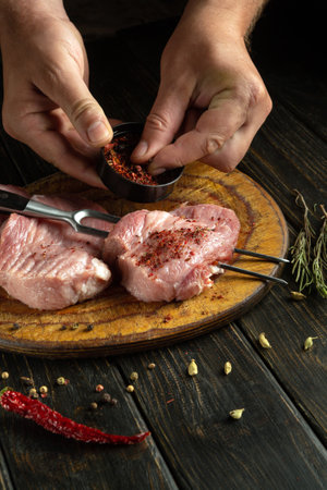 Meat with spices is prepared before the grill. The chef hands add aromatic seasoning to veal patties.の写真素材