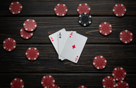 Playing cards with three of a kind or set and chips on a vintage table in a gentlemen's club after a successful game of poker. Low key concept of a nice and big win in a card game.の写真素材