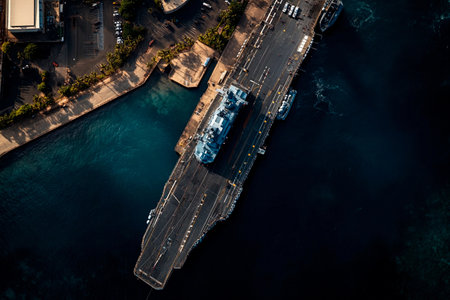 An impressive aircraft carrier rests in a vibrant harbor, its deck glinting in the warm light of evening.の素材