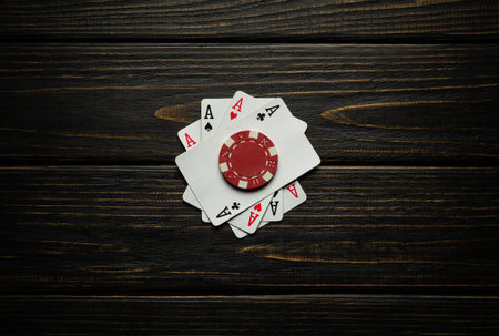Playing cards with a winning combination of four of a kind or quads and a red chip. Concept of luck...
