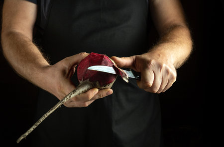 Hands skillfully peel a fresh beetroot using a sharp knife, emphasizing the vibrant color and texture of the vegetable. The atmosphere is warm and inviting, perfect for culinary creativity.の写真素材