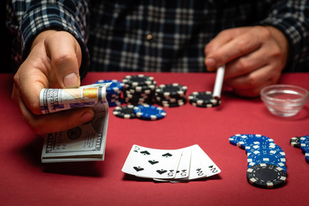 A lucky player bets on a winning combination of cards two pairs in a casino. A successful poker game with a good win and chips on a red table.の写真素材