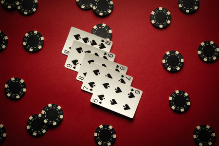 Several straight flush playing cards lie on a red table surrounded by chips. The atmosphere is charged with anticipation and poker strategy as players get involved in the game.の写真素材