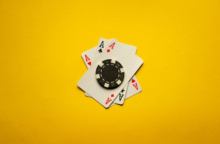 Three aces or a poker combination of three of a kind or set lie on a yellow table with one chip. The atmosphere is charged with winning excitement and poker strategy.の写真素材