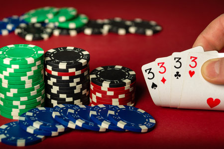 Player's hand holding playing cards with winning combination four of a kind or quads on red poker...