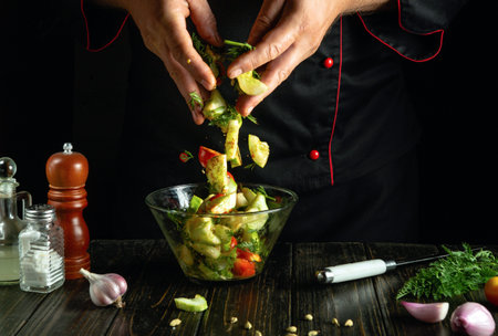 With expert hands, a chef tosses a mix of colorful vegetables into a clear bowl, creating a delicious salad. Aromatic herbs fill the air, enhancing the lively kitchen atmosphere.の写真素材