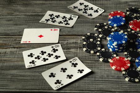 An evening card game with a winning combination of high cards and colorful poker chips scattered on a rustic wooden table. Excitement and excitement fill the air.の写真素材