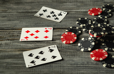 Upon closer inspection, three playing cards, a winning combination of three of a kind, set, can be seen laid out on a rustic wooden table along with chips, creating an exciting atmosphere for the game.の写真素材