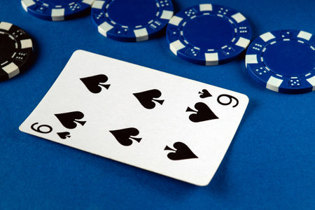 A nine of spades card is prominently displayed alongside various blue and black poker chips,...