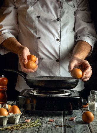 In a warm, inviting kitchen, a chef stands over a hot frying pan, ready to crack fresh eggs. The scene captures the essence of a morning cooking routine, with ingredients nearby.の写真素材