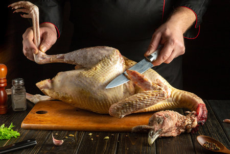 A skilled chef uses a sharp knife to carve a freshly killed bird on a wooden board in a warm kitchen. Ingredients and tools are nearby, enhancing the atmosphere of preparation.の写真素材