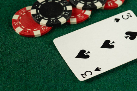A close-up view of a green felt tabletop showing poker chips and a playing card, setting the stage for an exciting game night filled with laughter and strategy.の写真素材