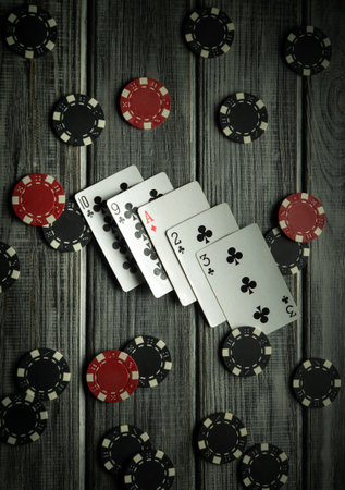 A casual game setting features playing cards showing various ranks alongside colorful poker chips...