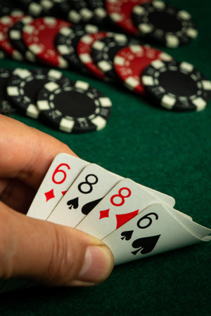 A player holds a strong poker hand showing two pairs, sixes and eights, while chips are scattered...