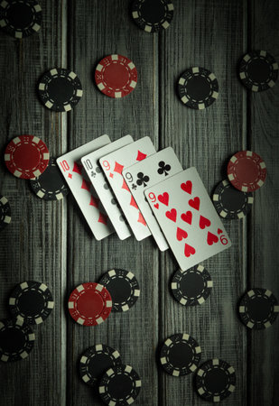 Several playing cards are displayed face up on a rustic wooden table surrounded by red and black poker chips. The setting feels lively, perfect for a gathering of friends or family.の写真素材