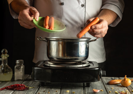 A chef holds a plate of uncooked sausages while placing them into a boiling pot on the stovetop. Steam rises, creating a warm kitchen atmosphere during evening cooking.の写真素材