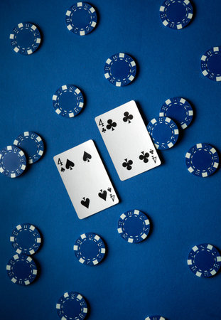 Two playing cards, both showing fours, sit center stage surrounded by an array of blue poker chips, representing a vibrant gaming experience during a lively casino night.の写真素材