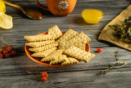 A plate of crunchy crackers is displayed on a rustic wooden table. Nearby, there are slices of...